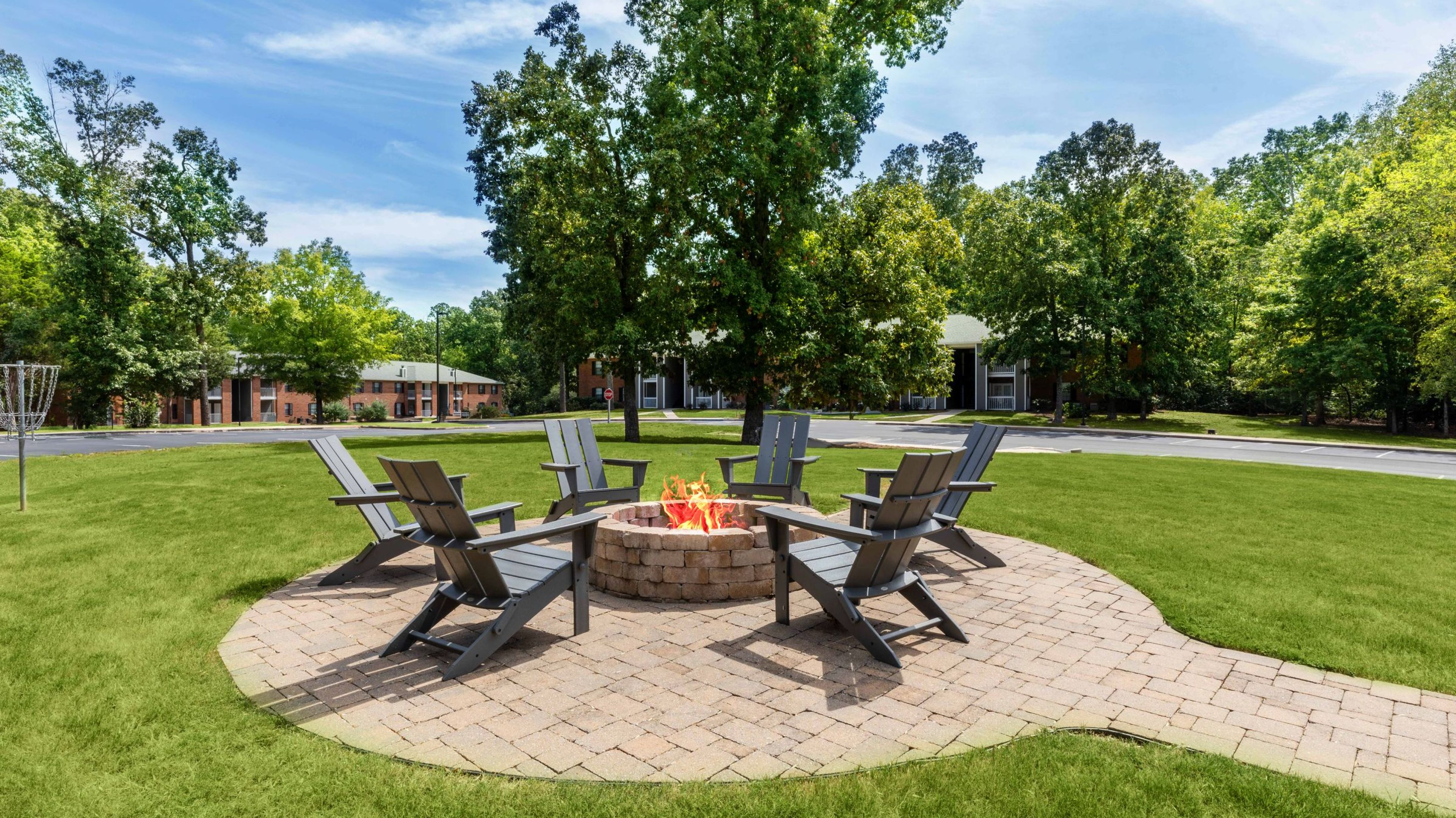 Hawthorne at the Ridge outdoor lawn area with pavilion covering tables and chairs, a grill area, and a firepit with surrounding chairs